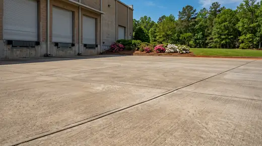 Concrete loading dock apron and truck pad at a distribution building in Savannah, GA, in clear late-morning sun.