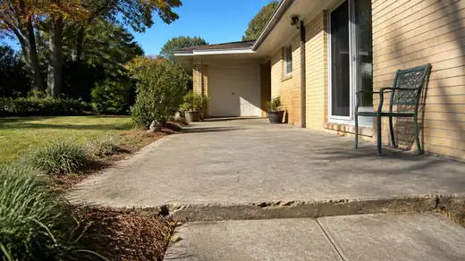 Worn back patio and steps of the kind a written estimate prices at a buff-brick ranch home in Savannah, GA, in clear late-morning sun.