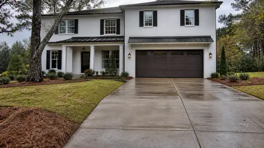 Settled garage approach slab the estimate would price to replace at a painted-white-brick two-story home in Savannah, GA, after a rain shower.